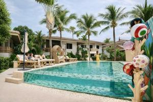 a pool at a resort with two people laying on chairs at Tulum Villa Resort Koh Samui in Bophut 