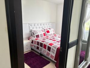 a small bedroom with a bed with red and white pillows at apta estudio oronegro amanecer in Armenia