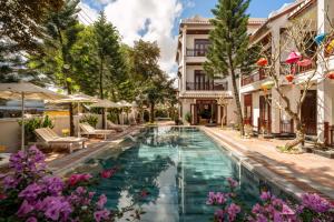 een zwembad midden in een gebouw met paarse bloemen bij Paradise Boutique Hoi An in Hội An