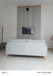 een witte bank in een woonkamer met een tv bij Casa Dwi Harmoni Sanur in Pesanggaran