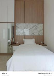 een slaapkamer met een groot wit bed met een houten hoofdeinde bij Casa Dwi Harmoni Sanur in Pesanggaran