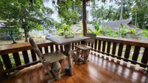 a wooden table and a chair on a porch at Casa Srithanu in Koh Phangan +1 photo