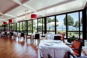 ein Restaurant mit weißen Tischen, Stühlen und Fenstern in der Unterkunft Hotel Stella del Benaco in Manerba del Garda