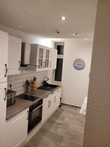 a kitchen with white cabinets and a sink at Kurvilla Apartments in Landstuhl