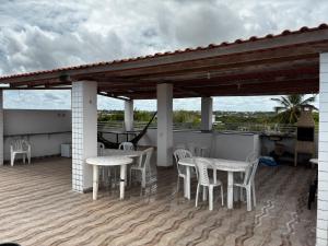eine Terrasse mit Tischen und Stühlen auf einem Dach in der Unterkunft Apartamento Duplex em Jacumã in Conde