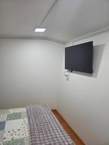 a bedroom with a bed with a tv on the wall at Cabaña full A1 in Punta Arenas