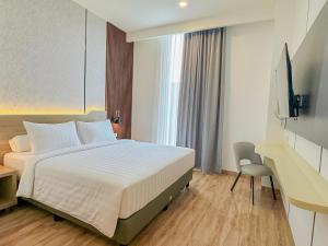 a bedroom with a bed and a desk and a television at Azana Style Hotel Jombang in Peterongan