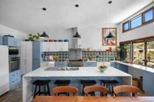 a kitchen with blue and white cabinets and stools at Hyams Reach Retreat in Erowal Bay