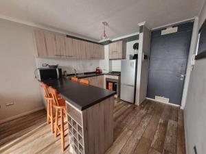 una cucina con piano di lavoro nero e pavimenti in legno di Departamento full equipado a Coquimbo 1 altra foto