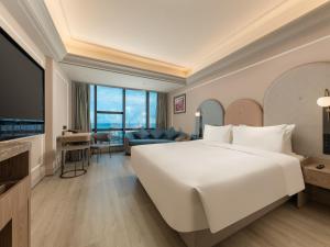 a bedroom with a large white bed and a living room at Mercure Danzhou Yangpu Seaview in Dongshan