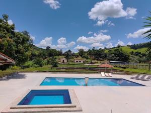 een zwembad met twee stoelen en een huis bij Sítio dos Rodrigues in Lindóia