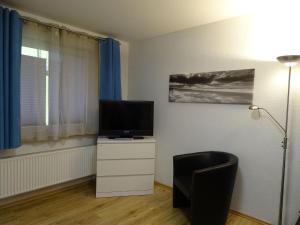 een woonkamer met een televisie op een wit dressoir bij Fewo-Seestern in Friedrichskoog