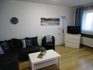 een woonkamer met een zwarte bank en een witte tafel bij Fewo-Seebaer in Friedrichskoog