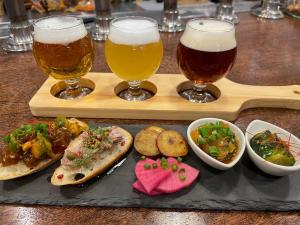 a tray with three glasses of beer and some food at TAP Inn MIURA in Miura