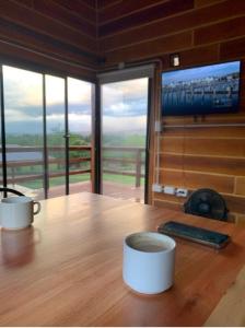 two cups of coffee on a wooden table with a television at San Yucac Relax in Los Reartes