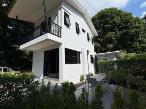 a white house with a balcony and a bench at Lucky home in the heart of thongsala in Thong Sala