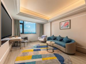 a living room with a blue couch and a tv at Mercure Danzhou Yangpu Seaview in Dongshan