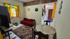 a living room with a red couch and a table at Atlantic Residence - Guaxindiba in São Francisco de Itabapoana