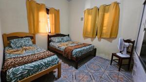 two beds in a room with yellow curtains at Atlantic Residence - Guaxindiba in São Francisco de Itabapoana