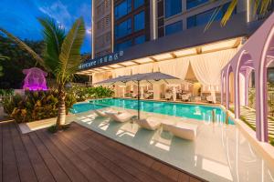 a swimming pool with white lounge chairs next to a building at Mercure Xishuangbanna in Jinghong
