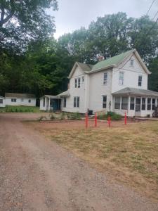 a white house with red posts in the yard at The Acorn at Oak Lodge in Palenville