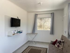 een witte woonkamer met een tv en een raam bij Casa nova bem aconchegante e tranquila in Biguaçu