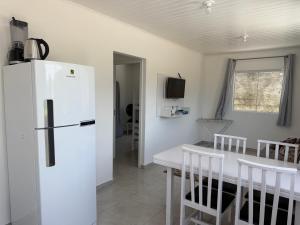 een keuken met een witte koelkast en een tafel en stoelen bij Casa nova bem aconchegante e tranquila in Biguaçu
