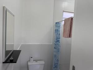 een witte badkamer met een toilet en een spiegel bij Casa nova bem aconchegante e tranquila in Biguaçu +10 foto's