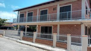 een stenen huis met een wit hek ervoor bij Pousada Villa&Mar in São Francisco do Sul