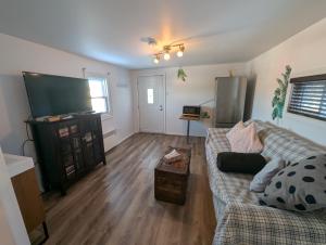 a living room with a couch and a flat screen tv at Le Namasté Auberge touristique in Lachute