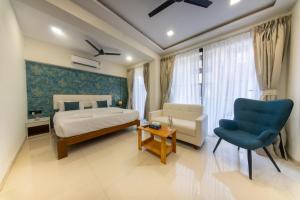 a bedroom with a bed and a blue chair at La Bela Casa Suites, Candolim in Candolim +18 photos
