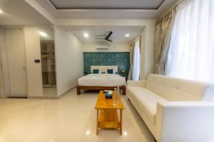 a living room with a white couch and a bed at La Bela Casa Suites, Candolim in Candolim