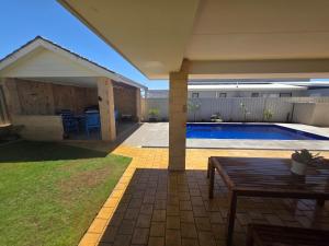 a patio with a table and a swimming pool at Sunset Beach B&B in Waggrakine