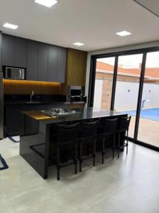 a kitchen with black cabinets and a counter with chairs at Casa de Luxo temporada in Paulínia