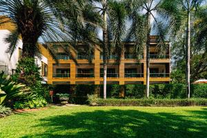 een groot geel gebouw met palmbomen ervoor bij The Bihai Hua Hin in Hua Hin