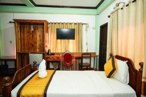 Schlafzimmer mit einem Bett, einem Schreibtisch und einem TV in der Unterkunft Bountang Mountain View Riverside Hotel in Vang Vieng