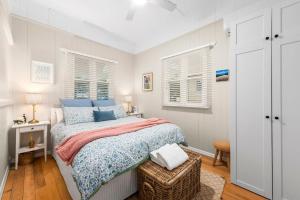 a white bedroom with a bed and two windows at Clark Cottage in Toowoomba
