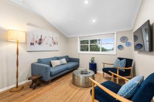 a living room with a blue couch and a table at Clark Cottage in Toowoomba