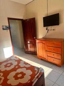 a bedroom with a bed and a dresser with a flat screen tv at Hostal Luxury Place in Bahía de Caráquez
