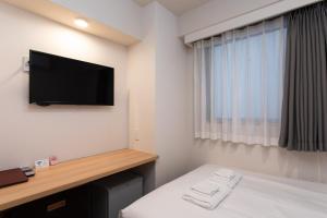 ein Hotelzimmer mit Bett und Flachbildfernseher in der Unterkunft Hopetree 天王寺 in Osaka