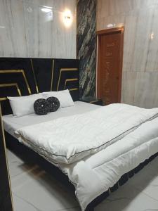 un grand lit blanc avec deux objets noirs dessus dans l'établissement Al IMRAN villa 2 bedroom apartment, à Lahore