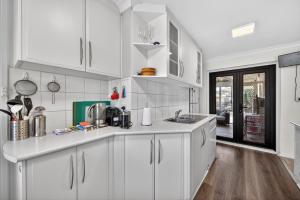 une cuisine blanche avec des armoires blanches et du parquet dans l'établissement Coastal 2-Bed Home with Pool & Spa, à Waikiki