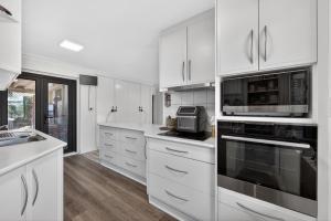 une cuisine blanche avec des armoires et des appareils blancs dans l'établissement Coastal 2-Bed Home with Pool & Spa, à Waikiki