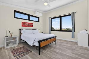 une chambre blanche avec un lit et une fenêtre dans l'établissement Coastal 2-Bed Home with Pool & Spa, à Waikiki 10 autres photos