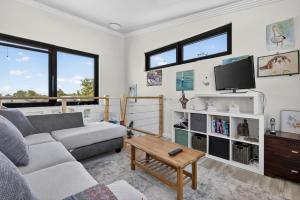 un salon avec un canapé et une télévision dans l'établissement Coastal 2-Bed Home with Pool & Spa, à Waikiki