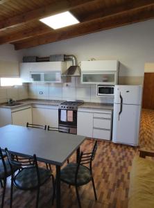 een keuken met een tafel, stoelen en een koelkast bij wind house - casa del viento in Perito Moreno