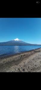 een met sneeuw bedekte berg op een waterlichaam bij Cabañas Loley - a pasos del lago in Puerto Varas