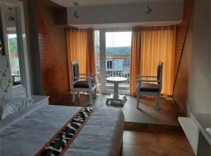 a bedroom with a bed and chairs and a balcony at Rockmont Inn in Taliparamba