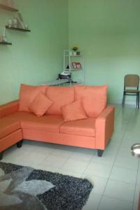 an orange couch sitting in a living room at Comfy Transit Tawau-Semporna in Tawau +2 photos