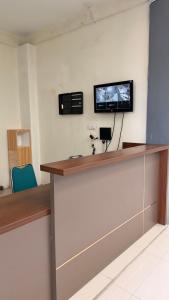 a reception desk with a flat screen tv on a wall at Elmo Living in Yogyakarta